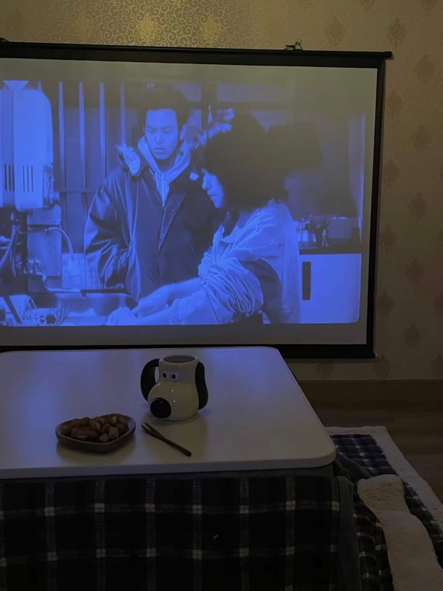 A film projected onto the 80-inch screen in front of a kotatsu table