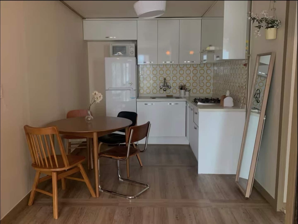 The actual kitchen with white cabinets and a wooden dining table