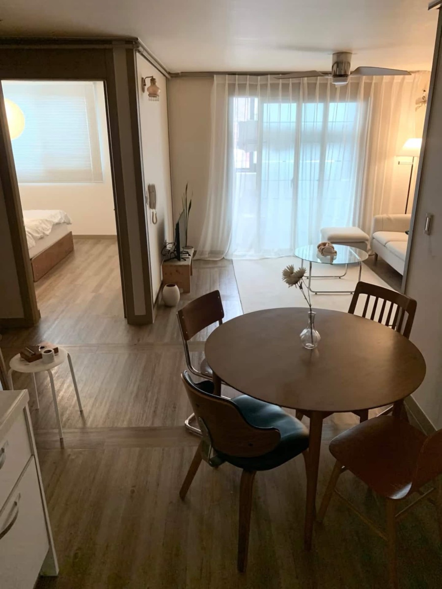 The actual stay with a wooden dining table, bedroom entrance and soft curtains